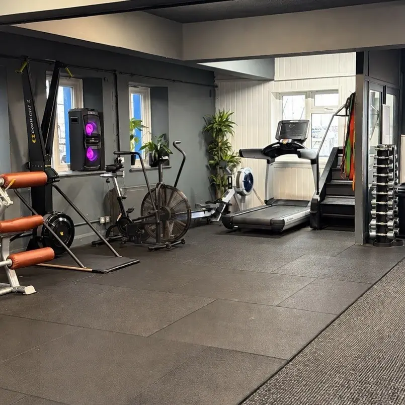 The gym floor at Box & Burn with an air bike, treadmill and rack of dumbbells